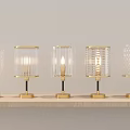 Multiple Lit Table Lamps With Glass Shades And Metal Bases On Wooden Shelf
