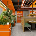 Vibrant Orange Restaurant Interior With Green Booths Dining Tables And Plant Decorations