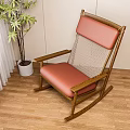 Comfortable Wooden Rocking Chair With Red Cushion Mesh Backrest And Green Plant