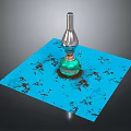 Green Glass Bottle With Silver Top On Blue Square Mat With Brown Spots