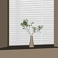 White Ceramic Vase Holding Green Leafy Twigs On Windowsill With White Blinds And Soft Light