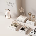 Stacked Books and Magazines with Decorative Hourglass Glass Lantern and Dried Feather in Minimalist Interior