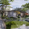 Tranquil Courtyard Garden With Lush Trees Pond Rocks Green Lawn And Metal Chairs