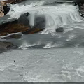 Natural Mountain Stream With Flowing Water And White Foam Over Rocks