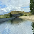 Scenic Concrete Water Canal in Arid Land With Trees Distant Mountains and Blue Sky