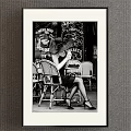 Vintage Black and White Woman Portrait Painting Seated in Wicker Chair at Outdoor Café