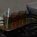 Daily Washing Essentials With Colorful Glass Cups Toothpaste Toothbrush And Green Leaves On Wooden Tray