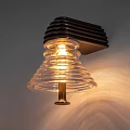 Illuminated Wall Lamp With Dark Base And Transparent Ribbed Glass Shade Emitting Warm Light