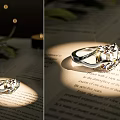 Elegant Silver Ring with Sparkling Gemstones on Book Pages Under Warm Light and Green Leaves