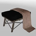 Modern Ottoman With Soft Brown Cushion And Wooden Legs Topped With Cozy Blanket