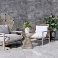 Rattan Chair And Table Set With Wooden Frame White Cushions Green Plants Against Gray Wall