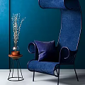 Blue Woven Accent Chair with Purple Pillow against Teal Wall and Side Table Vase