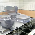 Stainless Steel Open Kitchen Setup With Large Pots Black Marble Countertop And White Tiled Wall