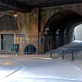 Arched Brick Underpass Area With Metal Fences Street Lamp And Curved Paved Road