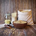Organic Oats in Burlap Sack and Wooden Bowl with Pasta in Glass Jar on Wooden Background
