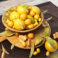 Yellow Lemons and Kumquats in Bowl on Wooden Cutting Board with Leaves and Peeled Rinds