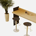 Light Wooden Bar Counter with Two Black Stools and Large Green Plant in White Pot