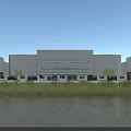 Modern Industrial Factory Building With White Exterior Large Windows Green Grass Waterfront And Blue Sky
