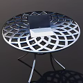 Round Metal Outdoor Table With Intricate Cutout Design And Laptop On Top