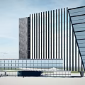 Modern Office Building Exterior With Glass Curtain Wall Vertical Stripes And Stone Accents