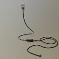 Black Cable Plugged Into Power Outlet On White Background With Coiled Wire On Floor