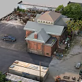 Red Brick Industrial Factory Building Surrounded by Trees With Black Vehicle and Machinery Yard