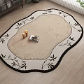 Decorative Oval Shaped Rug With Beige Center And Black Leaf Patterns On Wooden Floor