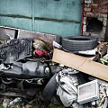 Waste Pile with Tire Wooden Board Fabric Old Electronics Cardboard Boxes and Red Brick Wall