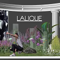LALIQUE Exhibition Showcase With Colorful Flowers Green Plants And Person Pointing
