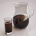 Clear Glass Pitcher with Dark Beverage and Small Glass Cup on White Table
