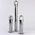 Three Silver Outdoor Lights With Tall Center Shorter Sides Cylindrical Poles Round Shades Metallic Finish