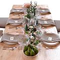 Elegant Dinnerware Set with Gray Napkins White Plates Wine Glasses and Green Plant Decorations