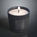Lit Candle In Black Container With White Wax And Decorative Label