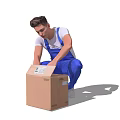 Man in Blue Overalls and White T-Shirt Kneeling to Handle Brown Cardboard Box