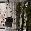 Black Hanging Chair With Cushion Ropes In Indoor Setting With Potted Plants Natural Light