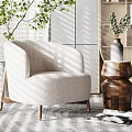 Beige Upholstered Armchair With Wooden Legs In Natural Light Near Green Plants And Wooden Shelves