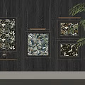 Black Framed Botanical Paintings With Floral Patterns Hanging On Dark Wooden Wall With Green Foliage