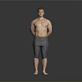 Shirtless Man Standing with Hands Behind Back in Gray Tight Pants on Gray Background