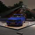 Blue Mercedes-Benz Car on Illuminated Display Platform With Stage Lights And Background Trees