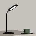Modern Black Desk Lamp With Curved Arm And Green Cup On Tabletop