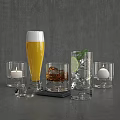 Assorted Drinking Glasses With Foamy Yellow Drink Ice Lime And Candle On Dark Wood Table