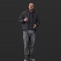 Man Wearing Black Hoodie And Jacket With Gray Jeans Standing Against Dark Background