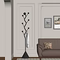 Black Tree Shaped Coat Rack With White Bathrobe Near Brown Sofa And Geometric Pillow