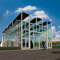Industrial Factory Building with Glass Facade in Green Outdoor Area Under Blue Sky and Clouds