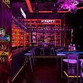 Vibrant Bar With E PARTY Neon Sign Shelves Bottles Counter Stools And Purple Red Lighting