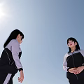 Students in School Uniforms Standing and Walking Outdoors With Blue Sky and Light Ground