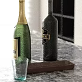 Green Champagne And Dark Wine Bottles On Marble Countertop With Brown Tray And Clear Cup