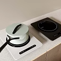 White And Black Induction Cooktops With Pot On Kitchen Counter And Wooden Cabinets