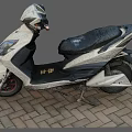 White And Black Electric Scooter With Black Seat Parked On Brick Pavement