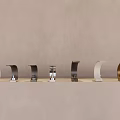 Multiple Modern Faucets In Various Colors And Designs On Light Countertop With Gray Wall